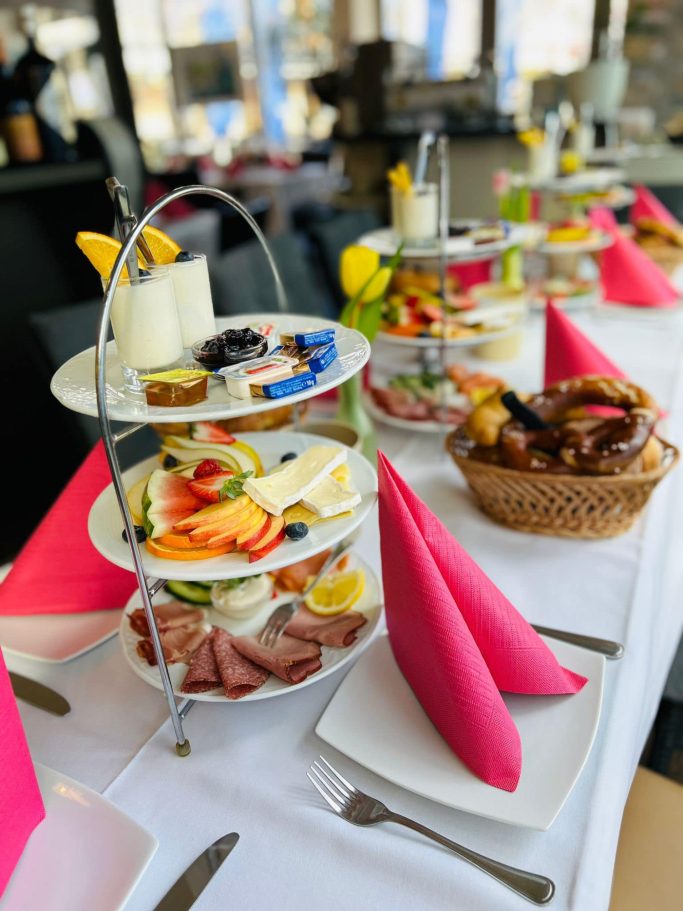 Festlich gedeckter Tisch mit mehreren Etagen voller Frühstücksvariationen und frischem Obst.